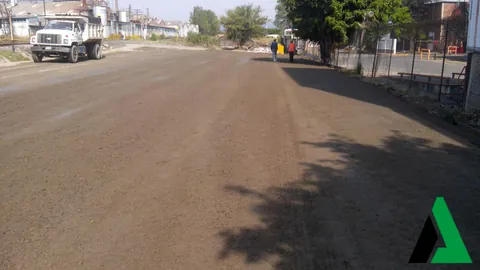 Base compactada de un camino urbano lista para pavimentar con camión de volteo al fondo