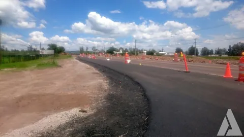 Carpeta asfáltica nueva en la ampliación de una carretera delimitada con conos naranjas