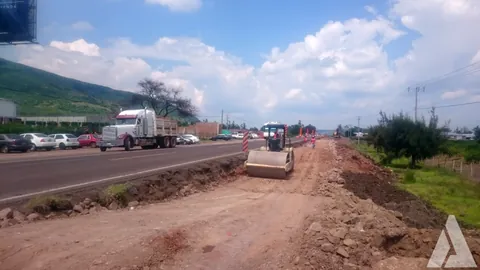 Compactador trabajando en terracerías junto a una carretera en operación con tráfico