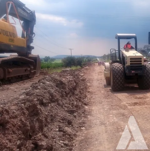 Excavadora Volvo y compactador trabajando juntos en la terracería de un camino rural