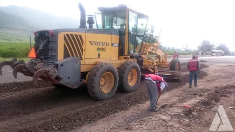 Motoconformadora Volvo nivelando terracería con trabajadores revisando el material