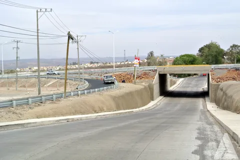 Paso a desnivel terminado con muros de concreto, guarniciones y barreras metálicas de protección