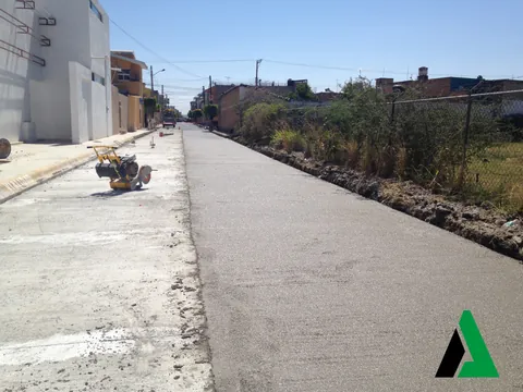 Calle urbana con pavimento de concreto hidráulico terminado y cortadora de juntas en la banqueta