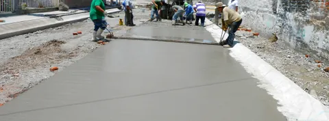 Cuadrilla colando y nivelando un pavimento de concreto hidráulico en una calle urbana