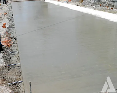 Pavimento de concreto hidráulico recién colado con varillas de junta en el borde de la calle