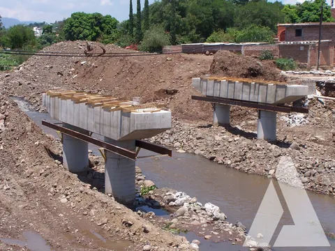 Pilas y trabes prefabricadas de concreto de un puente en construcción sobre un arroyo