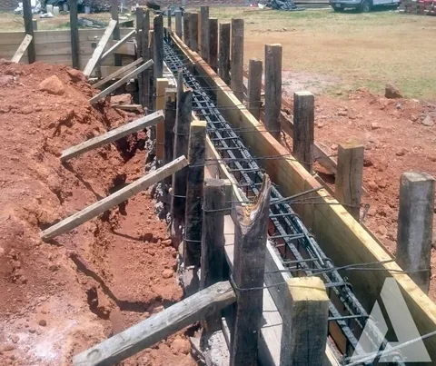 Trabe de cimentación armada con varilla y cimbra de madera apuntalada a lo largo de la excavación