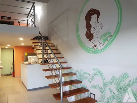Escalera recta de estructura metálica con peldaños de madera que sube al mezzanine de un local comercial remodelado