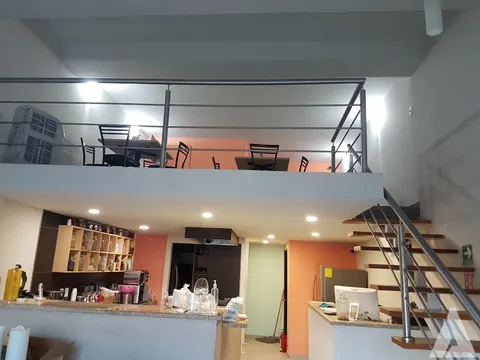 Mezzanine con barandal metálico y escalera de acero construido sobre la barra de un local comercial